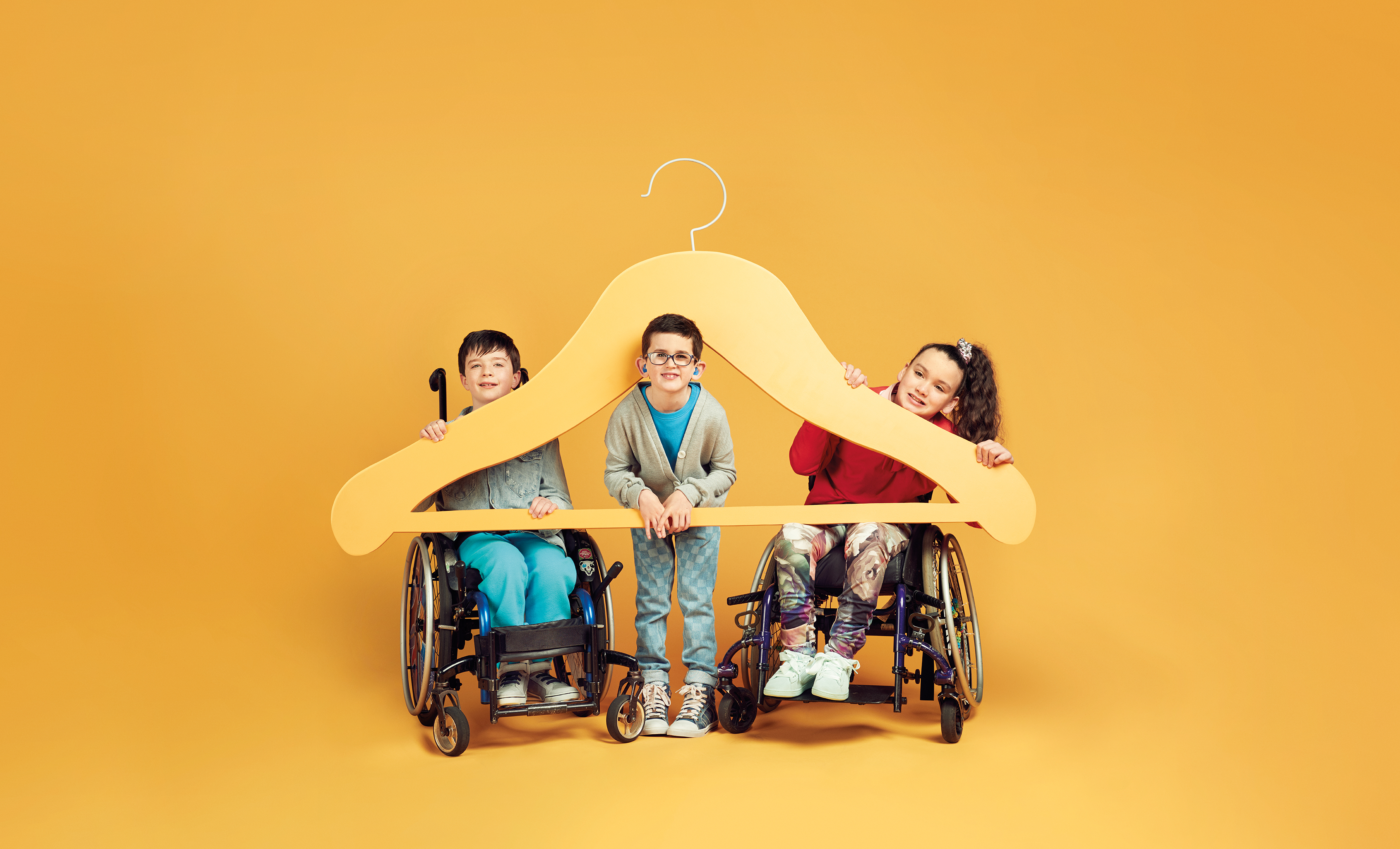 Three children including two wheelchair users with a giant hanger