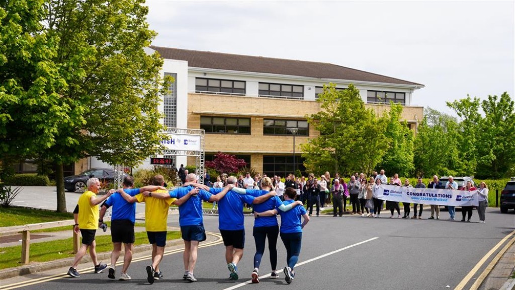 7 people walk arm in arm towards marathon finish line